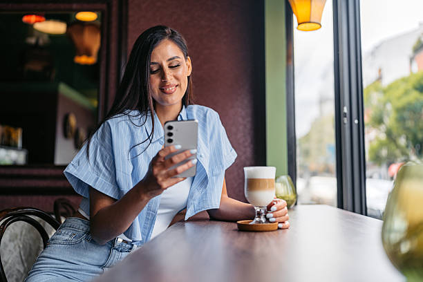 istock Young Woman Drinking Coffee While Using Her Phone In A Coffee Shop 2226614546