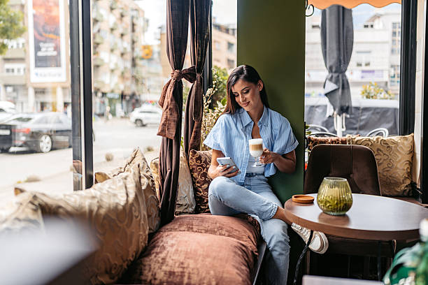 istock Young Woman Drinking Coffee While Using Her Phone In A Coffee Shop 2226614869