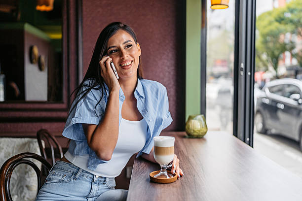 istock Young Woman Drinking Coffee While Talking On Her Phone In A Coffee Shop 2226615131