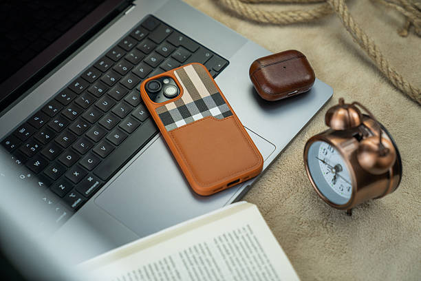 istock Smartphone, Bluetooth Earbuds, and Desk Clock on a Gray Laptop 2226616188