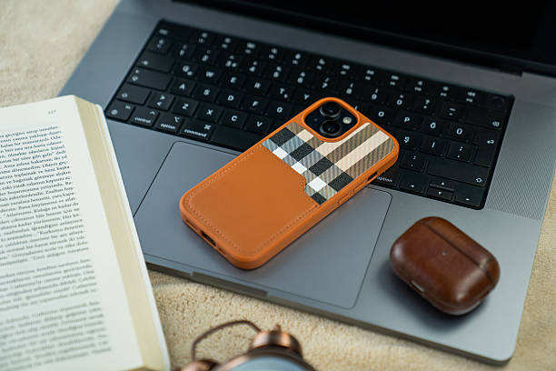 Smartphone, Bluetooth Earbuds, and Desk Clock on a Gray Laptop