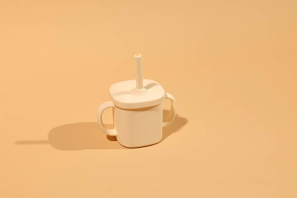 istock Cream-colored silicone baby sippy cup with straw, minimalist pastel background, soft lighting. 2226616445