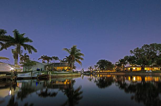 Night view of canal with palm trees and houses in Cape Coral Florida with reflections