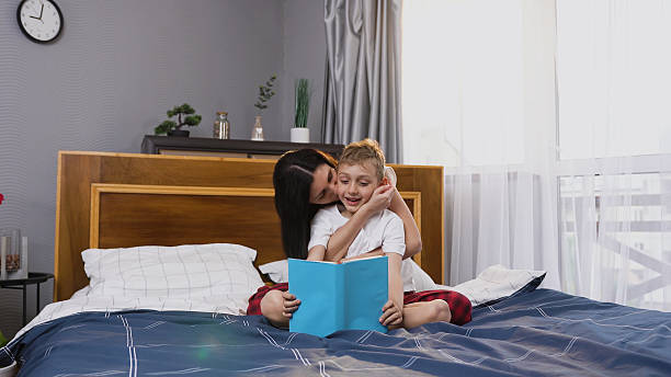 istock Splendid satisfied 30-aged woman playing with her handsome 8-aged son while he reading interesting book in contemporary sleeping room ,front view 2226617167