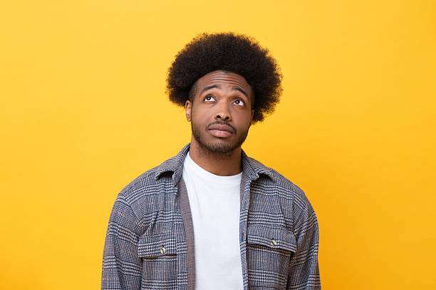 istock Thoughtful man looking up with curious expression on yellow background 2226622847