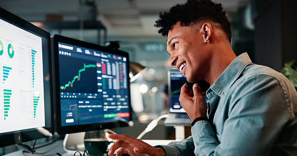Phone call, happy and man by computer screen in office with trading at night for investment account. Technology, communication and male financial analyst with stock market risk analysis in workplace.