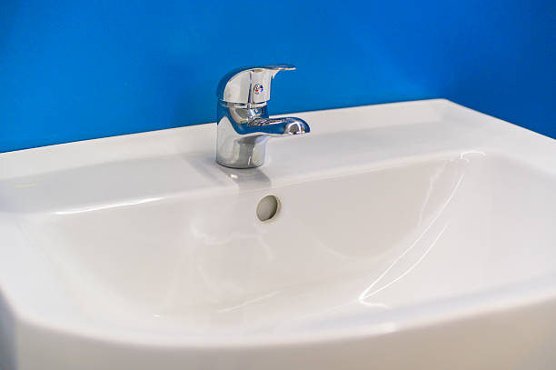 istock Modern chrome faucet on white ceramic sink in bathroom with blue wall 2226626491