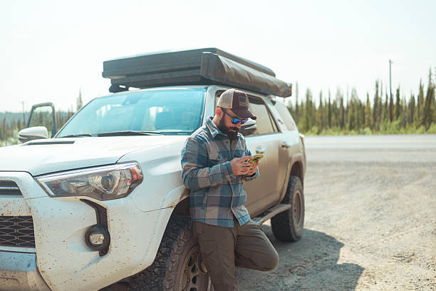 istock A man is leaning against his SUV and using a smartphone 2226629613