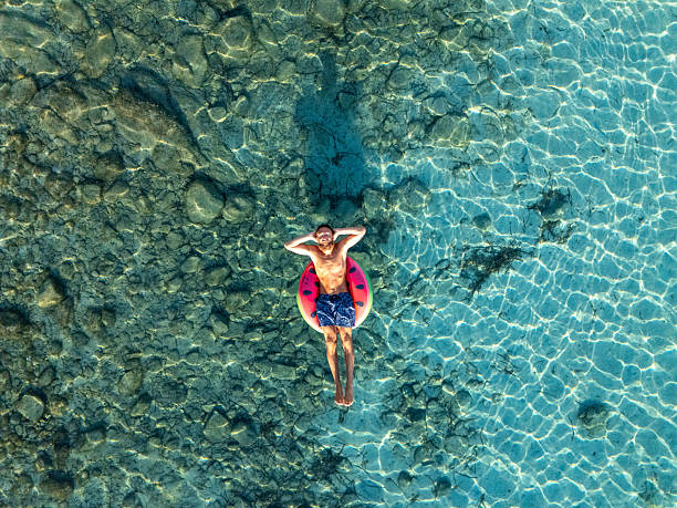 istock Drone view of man floating on inflatable watermelon on clear blue water 2226629705