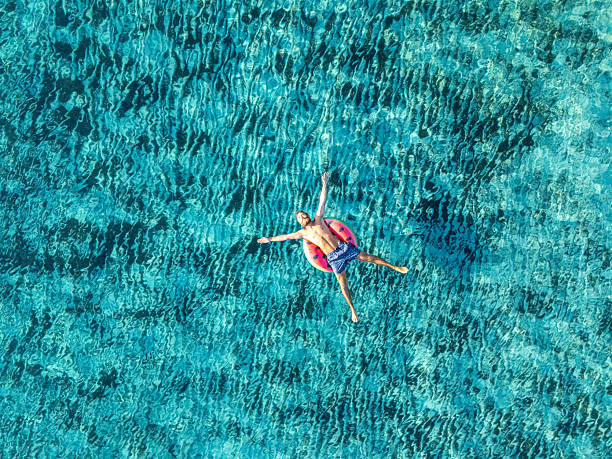 istock Drone view of man floating on inflatable watermelon on clear blue water 2226629996