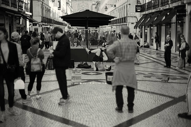 Lisbon, POrtugal - Mars 16, 2024: A street artist performs a juggling act with a soccer ball at the Rua Augusta street in Lisbon downtown.