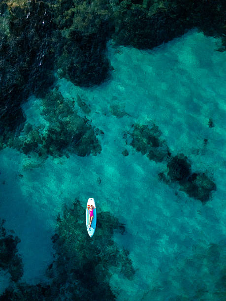 istock Directly Above: Paddleboarder Floating Near Rocky Shoreline 2226631640
