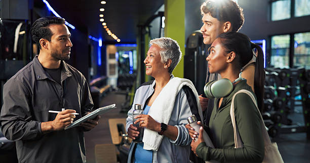Man, group and sign up with tablet at gym for class, registration or smile with exercise tips. People, personal trainer or membership app for welcome to club, schedule or discussion at fitness center