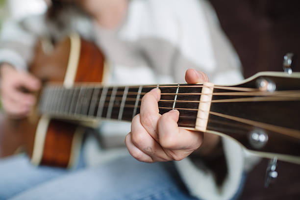 Young woman sitting on a sofa and playing guitar