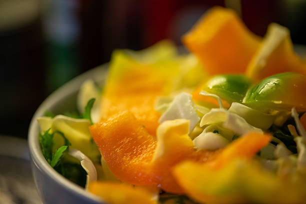 A vibrant kitchen scene of a woman slicing cucumbers, lettuce, and other vegetables, capturing the freshness and healthiness of a homemade salad in progress.
