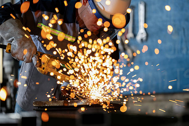 istock Technician performs metal grinding on a production line in a steel mill. Protective gear ensures safety while the rotary blade carves through iron, producing bright flashes and motion in a high-temperature, high-risk environment. 2226637060
