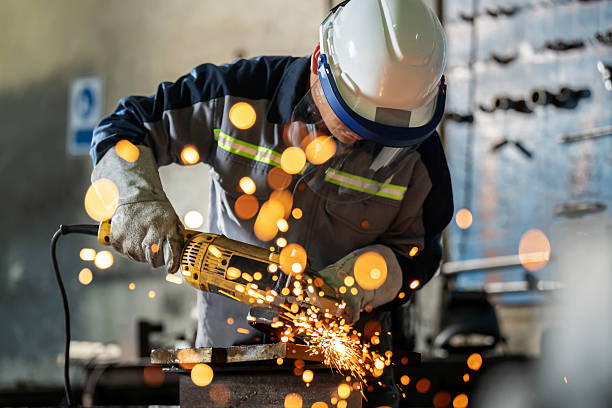 istock Worker in protective suit operates heavy-duty grinding equipment in a factory setting. Flying sparks illuminate the workshop, showcasing strength, precision, and occupational safety in a demanding metalworking environment. 2226637064
