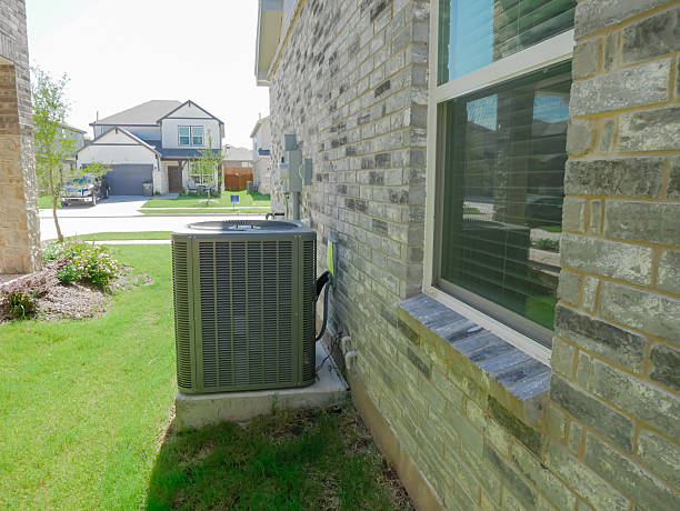 istock Modern AC outdoor condenser system on concrete pad with ductwork and electrical conduit enter the house, grassy yard, brick siding windows and blinds of new construction home in Princeton, Texas 2226639496