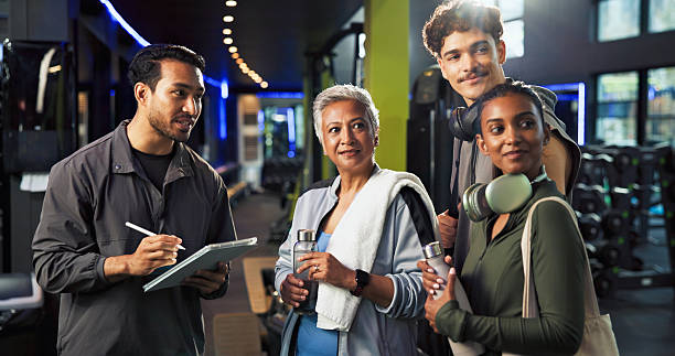 istock Personal trainer, talking and group with membership in gym, explaining and info for training routine. Wellness, instructor and man with tablet for digital sign up, online and benefits of health club 2226642482
