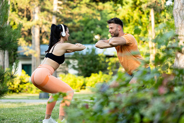 Fitness people exercising and doing squats together in the park.