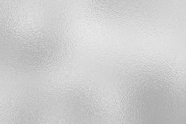 istock gray foil glass texture background. Abstract gradient bright light reflection and shiny rough texture surface. The light softly scatters, creating a shimmering effect with varying tones of silver gray 2226657457
