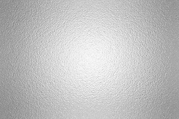 istock gray foil glass texture background. Abstract gradient bright light reflection and shiny rough texture surface. The light softly scatters, creating a shimmering effect with varying tones of silver gray 2226657696