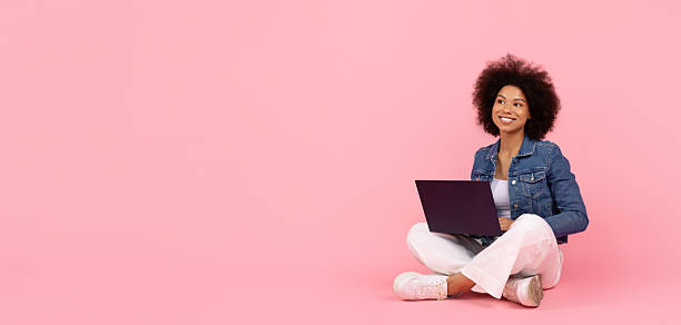 istock Young African American woman using laptop while sitting on floor 2226658187