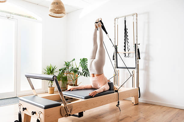 istock Woman practicing pilates using reformer bed and straps in bright studio 2226659833