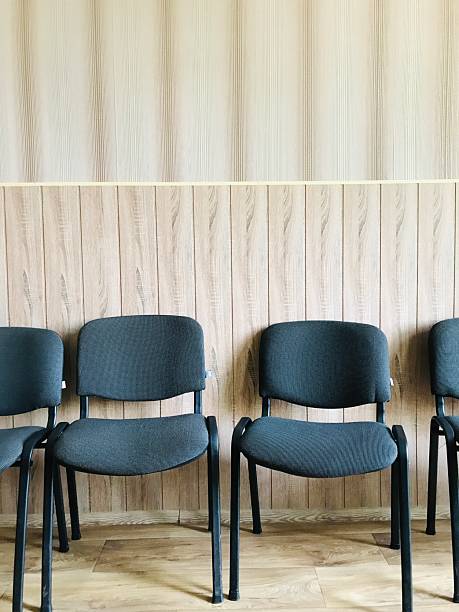 istock Empty chairs lined up against a wooden wall in a waiting area 2226664230