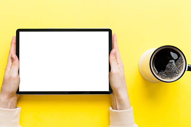 Close up image woman hands holding digital tablet with blank copy space screen for your text message or promotional content om table with cup of coffee. hands of a woman holding blank tablet device.