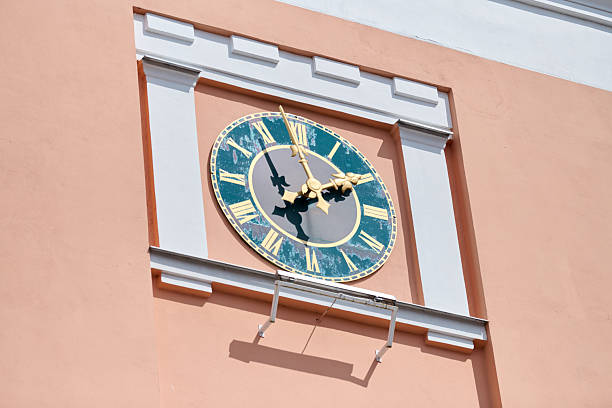 Gvardeysk, Russia - May 13, 2025 - Ornate town hall clock features mechanical dolls, showcasing cultural charm. Set against salmon-hued wall under bright daylight, its vibrant attraction