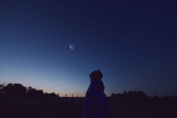 istock Silhouette of a man observing Moon, Milky Way stars, planets and other celestial objects from a dark countryside location. 2226671521