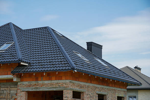 istock A partially completed house features a sleek roof design, large windows, and a traditional chimney, surrounded by a tranquil landscape and blue sky 2226673576