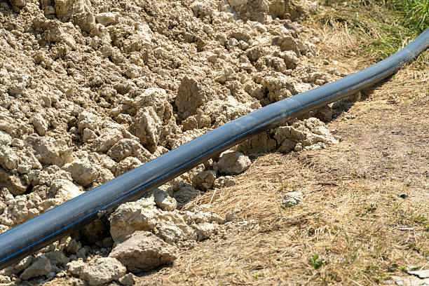 istock A black pipe is seen resting on a mound of freshly dug soil at a construction site, with patches of dry grass present under bright sunlight, indicating ongoing work 2226673582