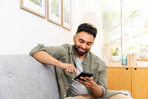 istock Happy young man using smart phone on sofa at home 2226673777