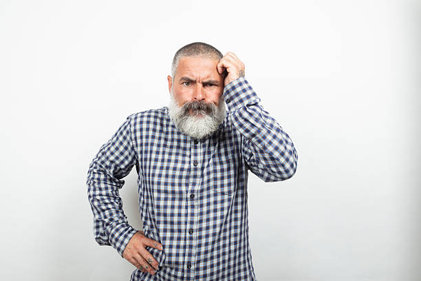 Portrait of a confused mature man scratching his head against a white background