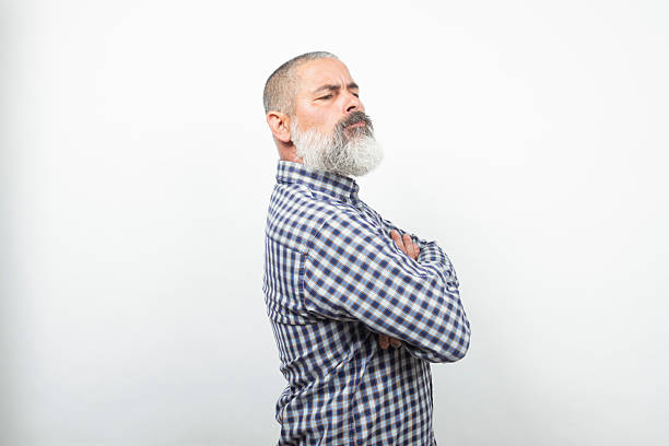 istock Mature man with crossed arms and skeptical expression on white background 2226677900