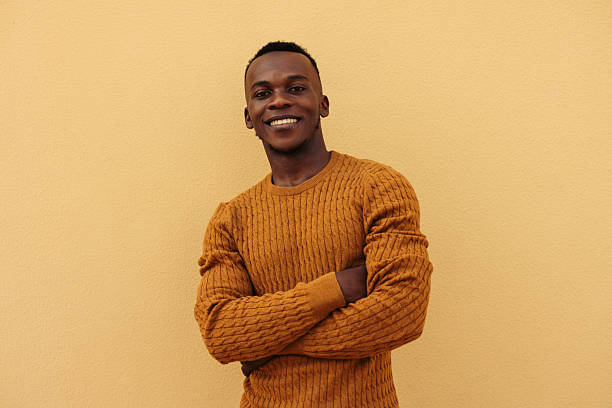 istock Smiling man posing confidently against a yellow background with folded arms 2226682230