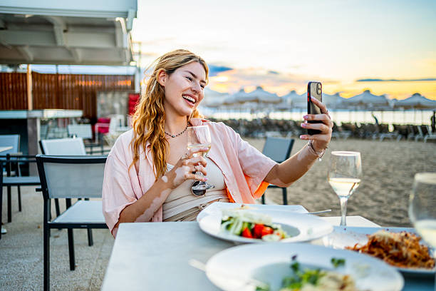 istock Happy young woman taking a selfie while having dinner at beach restaurant 2226684285