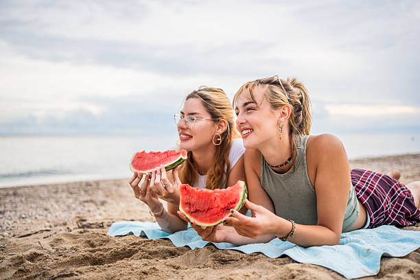 istock Two young women lying on the beach eating watermelon slices 2226684562