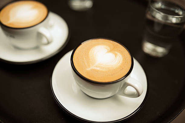 Shot of two cups of cappuccino with heart shaped latte art.