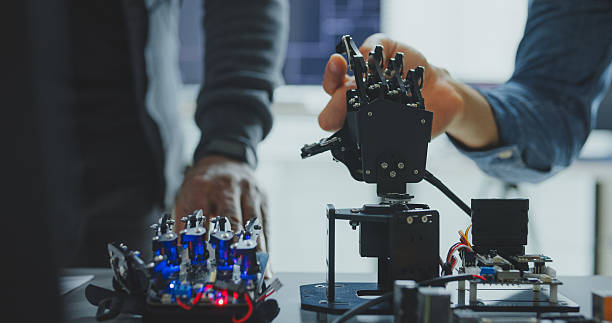 istock Closeup of Black and Hispanic male engineers programmers work together on robot hand prototype, use computer control robotic arm circuit in tech office. Software developer, artificial intelligence. 2226685073