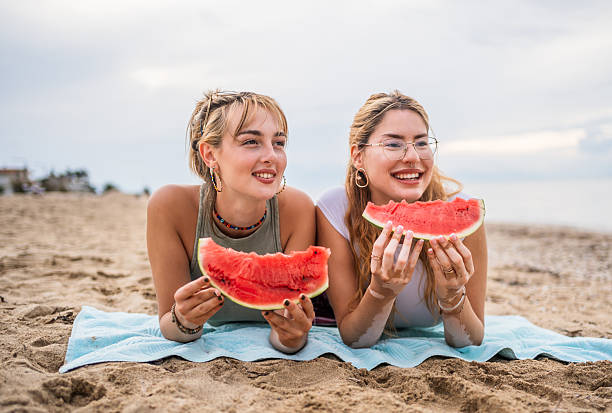 istock Two young women lying on the beach and eating watermelon 2226685265