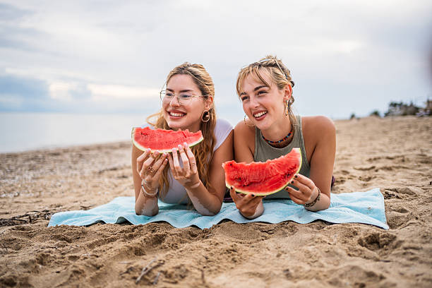 istock Two smiling young women eating watermelon on the beach 2226685678