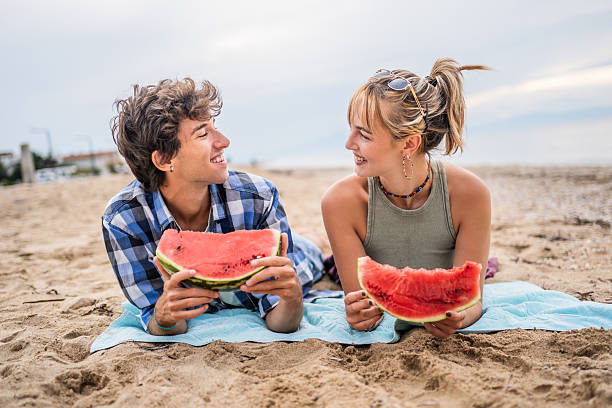 istock Young couple enjoying watermelon on the beach 2226685706