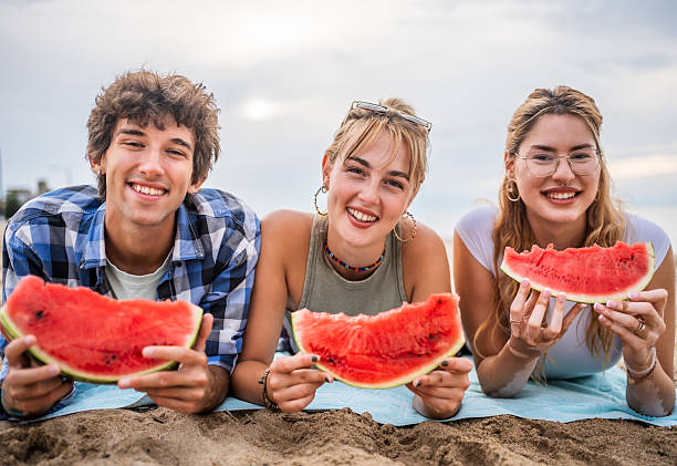 istock Young friends enjoying watermelon on the beach 2226685753