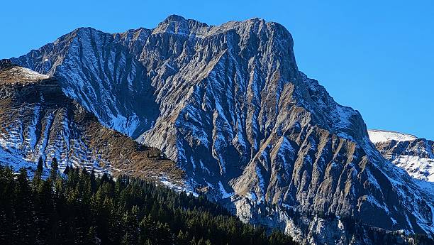 istock Impressive Close-Up of a Mountain Flank with Detailed Shading and Light Snowfall under a Steel-Blue Sky in the Swiss Alps 2226688973