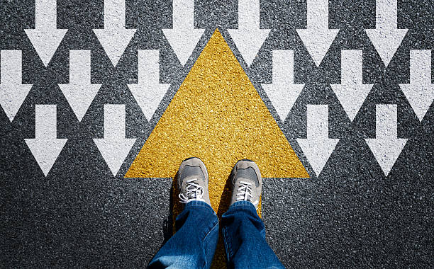 istock Man standing on the yellow big arrow, while many white small arrows in the opposite direction on the opposite side 2226692789