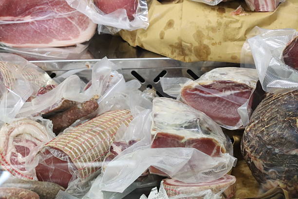 Variety of vacuum packed cured pork products displayed on a market stall, offering a selection of traditional italian delicacies