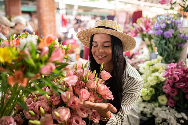 istock Woman Smiling While Smelling Flower Stall Blooms 2226699604